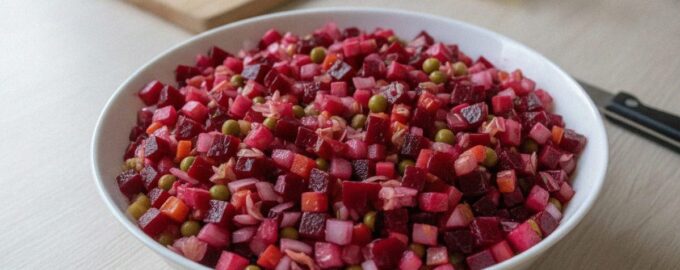 Классический винегрет в белой миске на кухонном столе